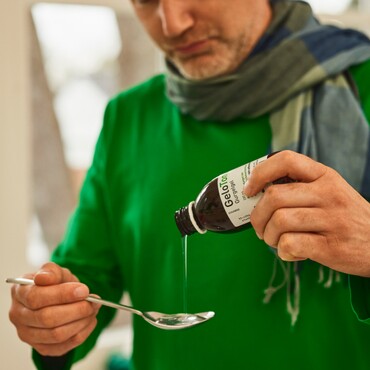Schritt 1 der Anleitung von GeloTonsil® bei Halsschmerzen: Mann gibt das Gurgelgel auf einen Esslöffel, um es anschließend in den Mund geben und gurgeln zu können.